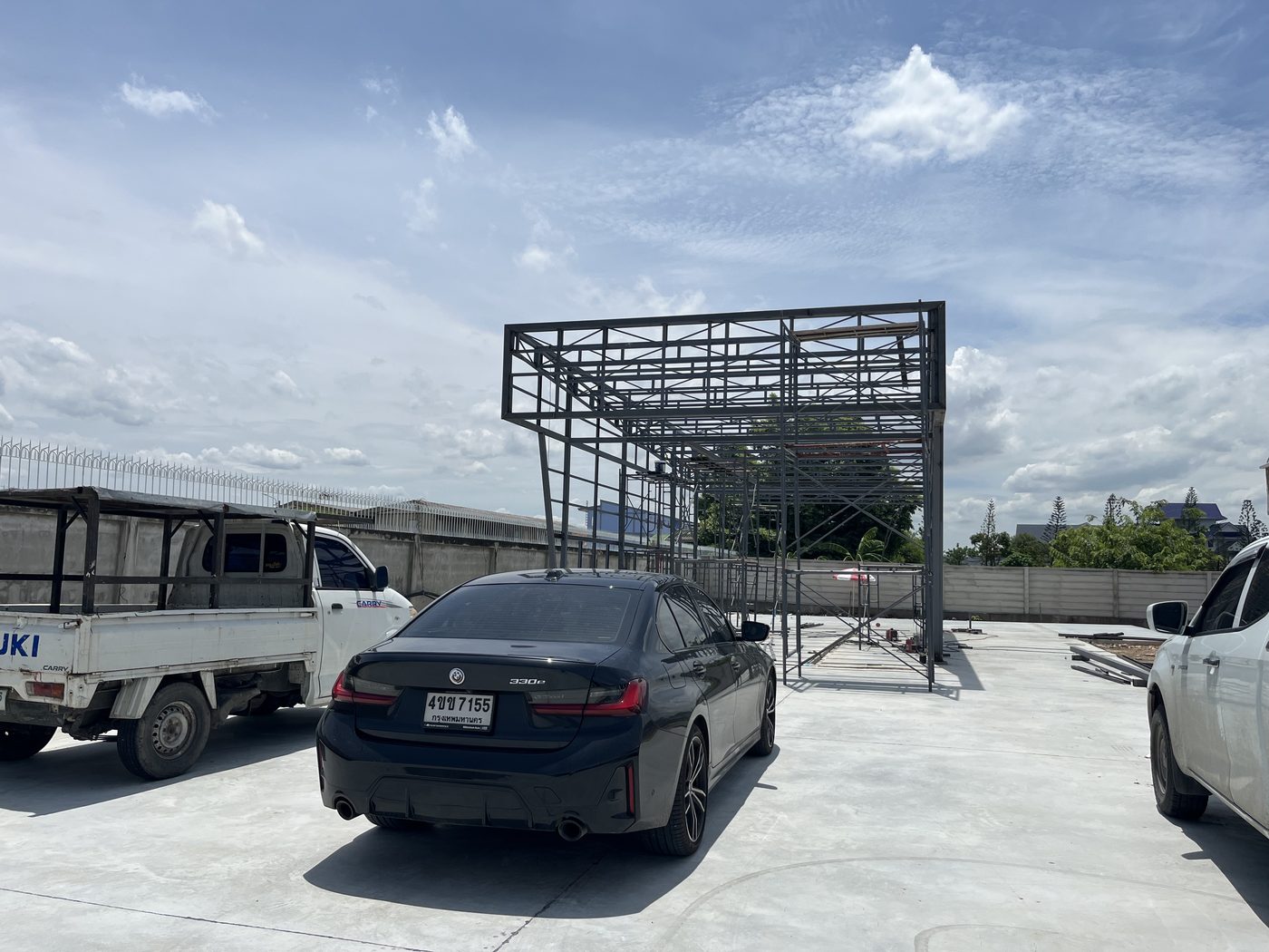 โครงเหล็ก ORCA Auto Wash มุมทางเข้า รถยนต์จอดหน้าไซต์ก่อสร้าง — APW