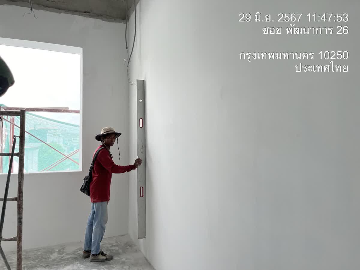 ช่างทาบระดับน้ำตรวจความเรียบผนังฉาบในห้อง