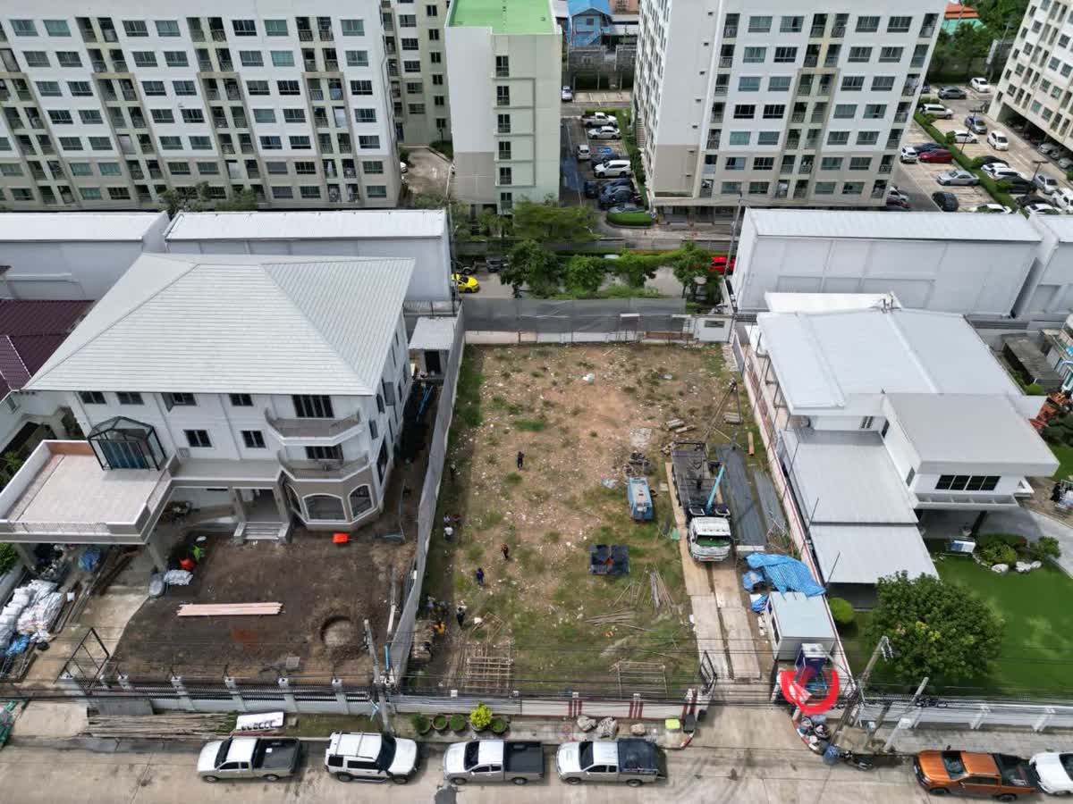 ภาพมุมสูงที่ดินเปล่าก่อนเริ่มก่อสร้าง ล้อมรอบด้วยบ้านและคอนโด