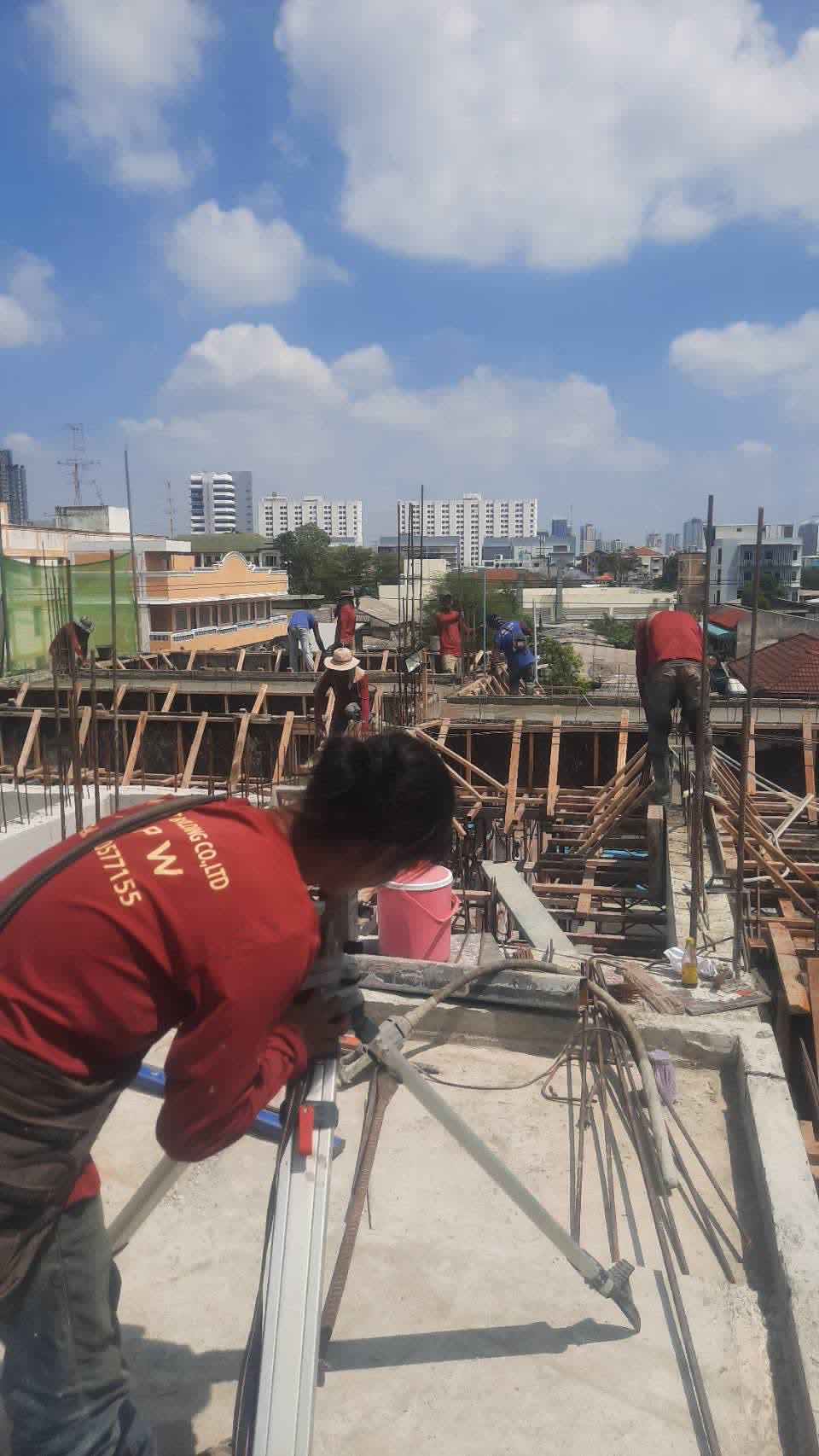 ช่างสำรวจตั้งกล้องระดับบนดาดฟ้า พื้นหลังเป็นวิวเมืองกรุงเทพฯ